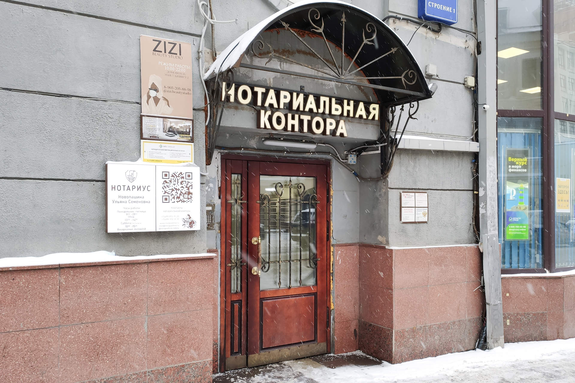 Вход в здание под козырьком с вывеской нотариальной конторы и табличками на фасаде.